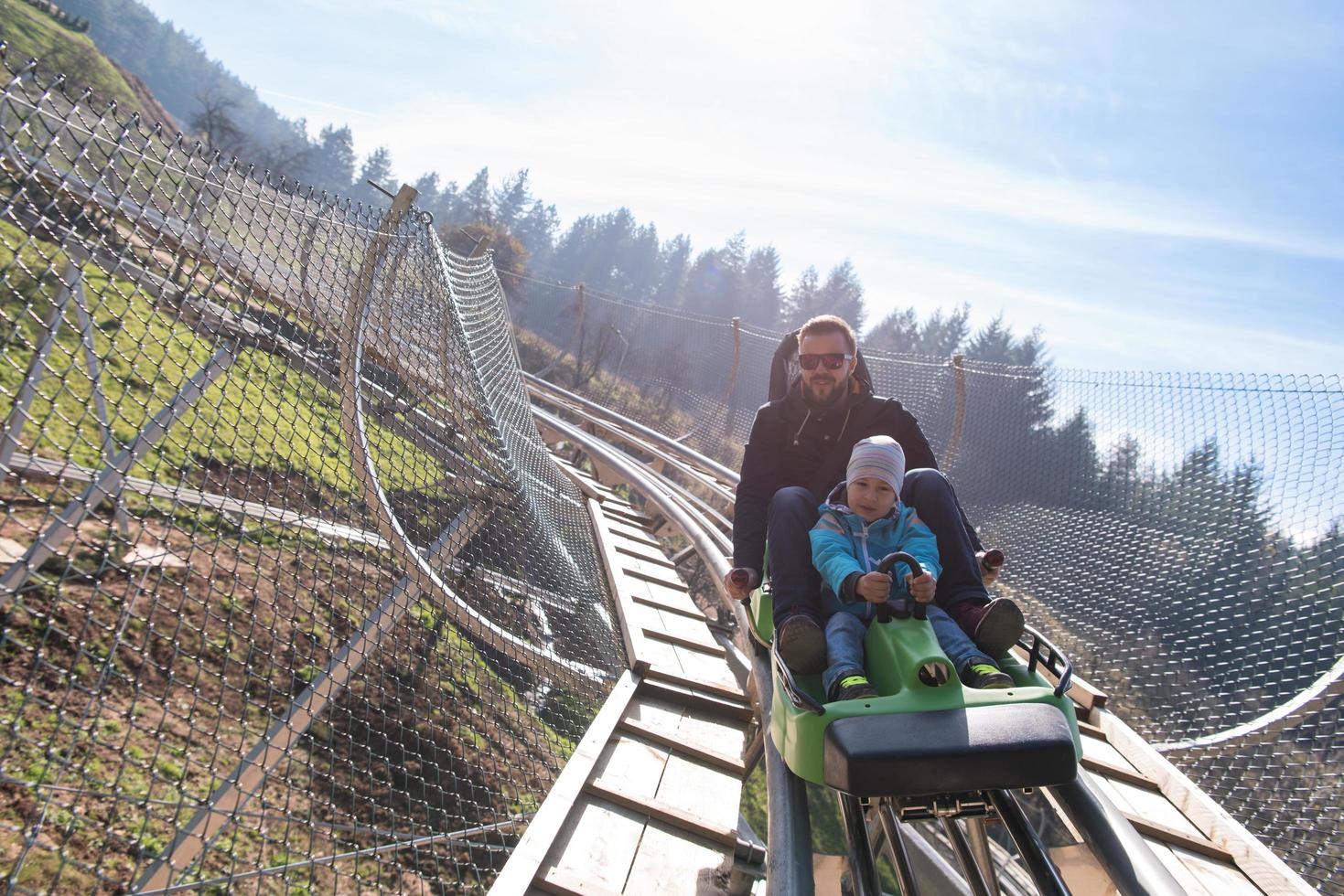 father and son enjoys driving on alpine coaster photo