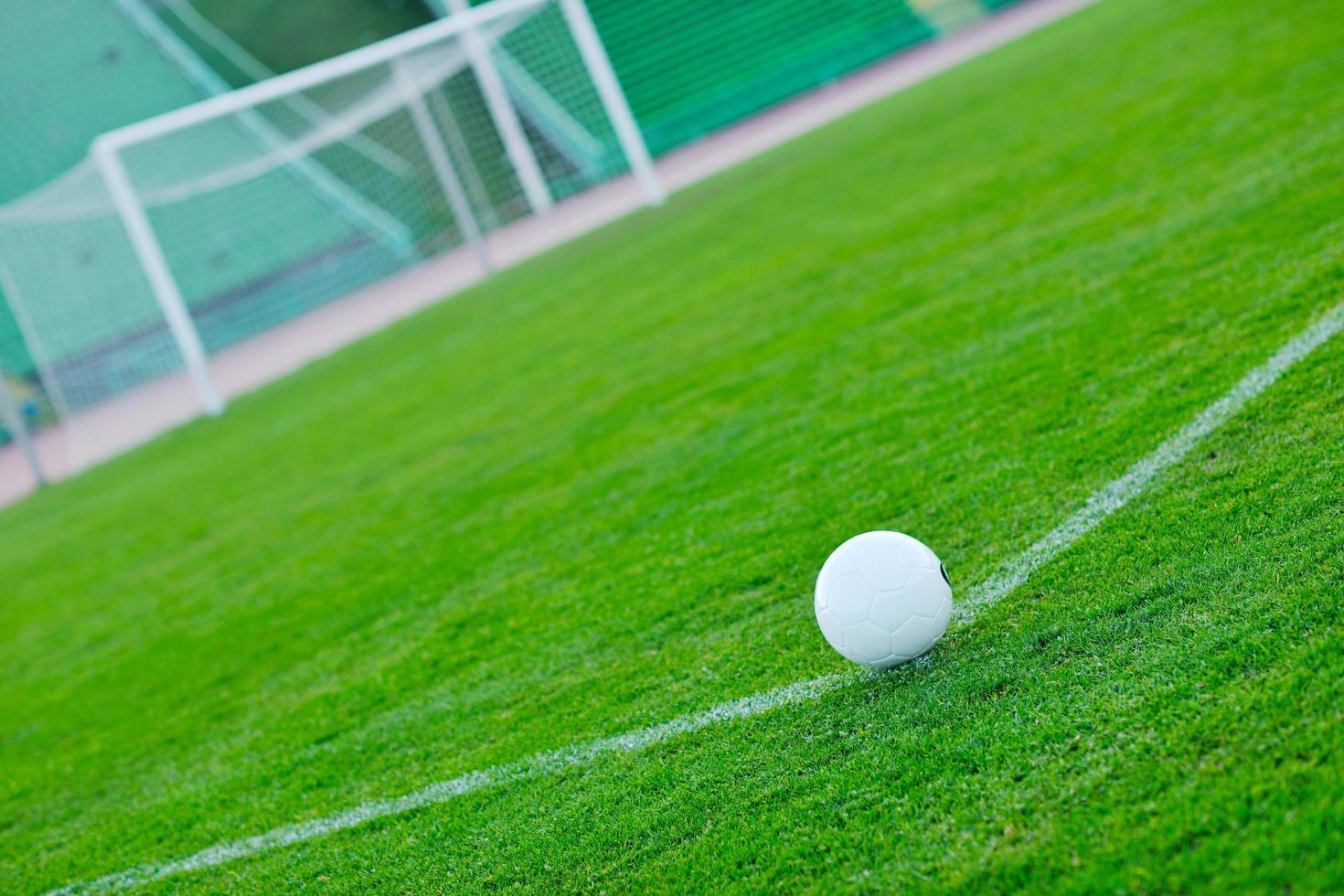 Soccer ball on grass at goal and stadium in background photo