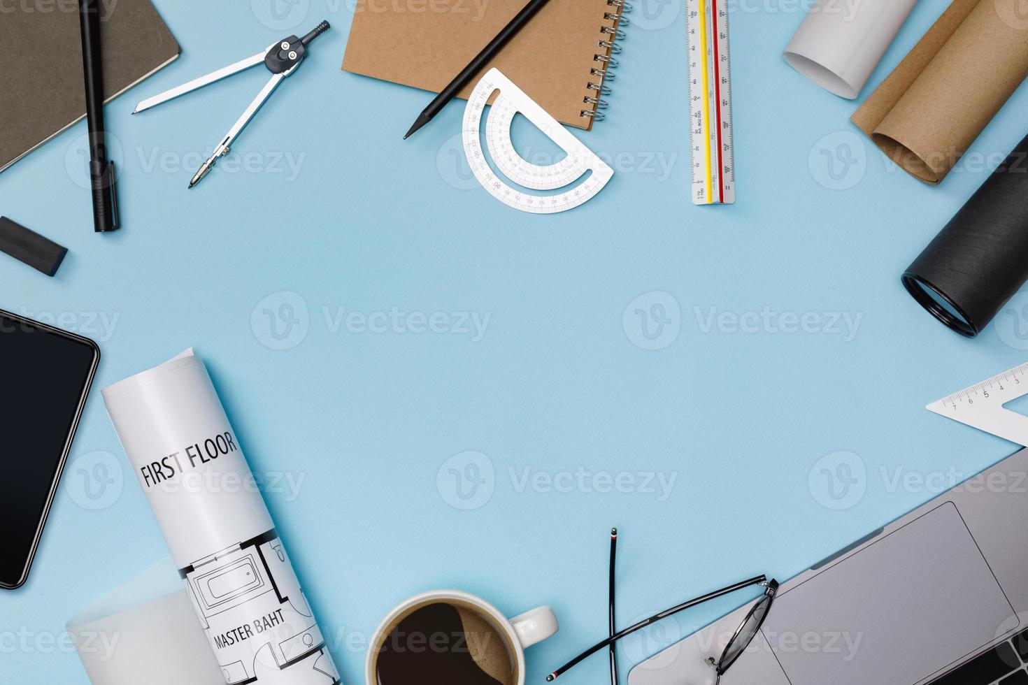 Top view workspace mockup of architectural project with laptop computer, architectural project plan, engineering tools, office supplies and hot coffee cup on blue desk empty space isolated on blue photo