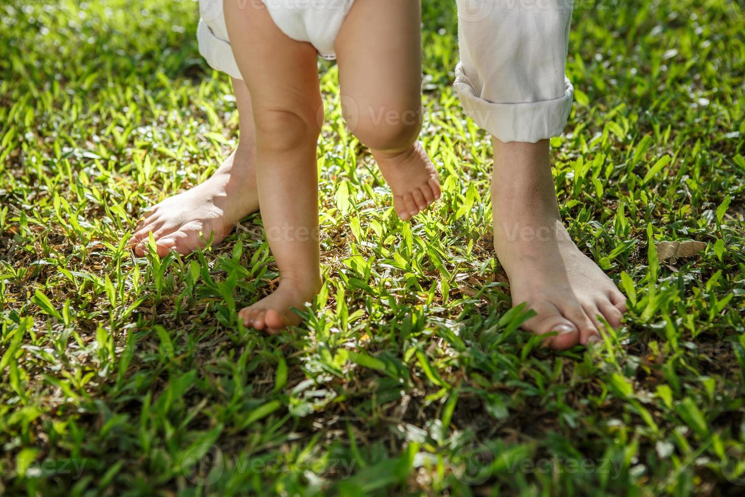 Closeup portrait of a mother teaching baby to walk outdoors. photo