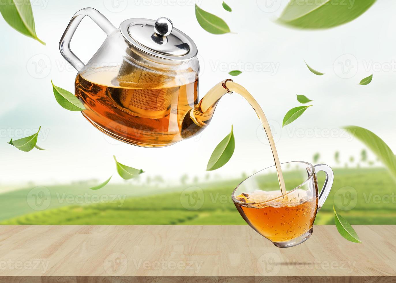 Jug pouring hot tea into glass cup with flying whirl green tea leaves in the air in tea plantations, Healthy products by organic natural ingredients concept, Empty space in studio shot photo