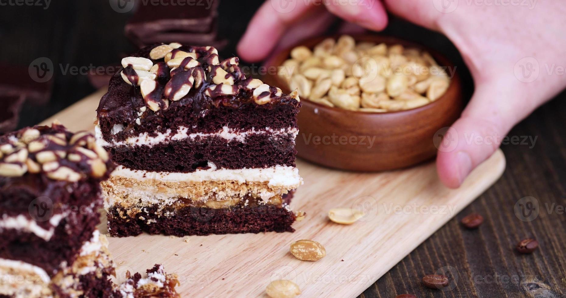 rearrange the bowl of nuts near the chocolate cake with nut filling and peanuts photo