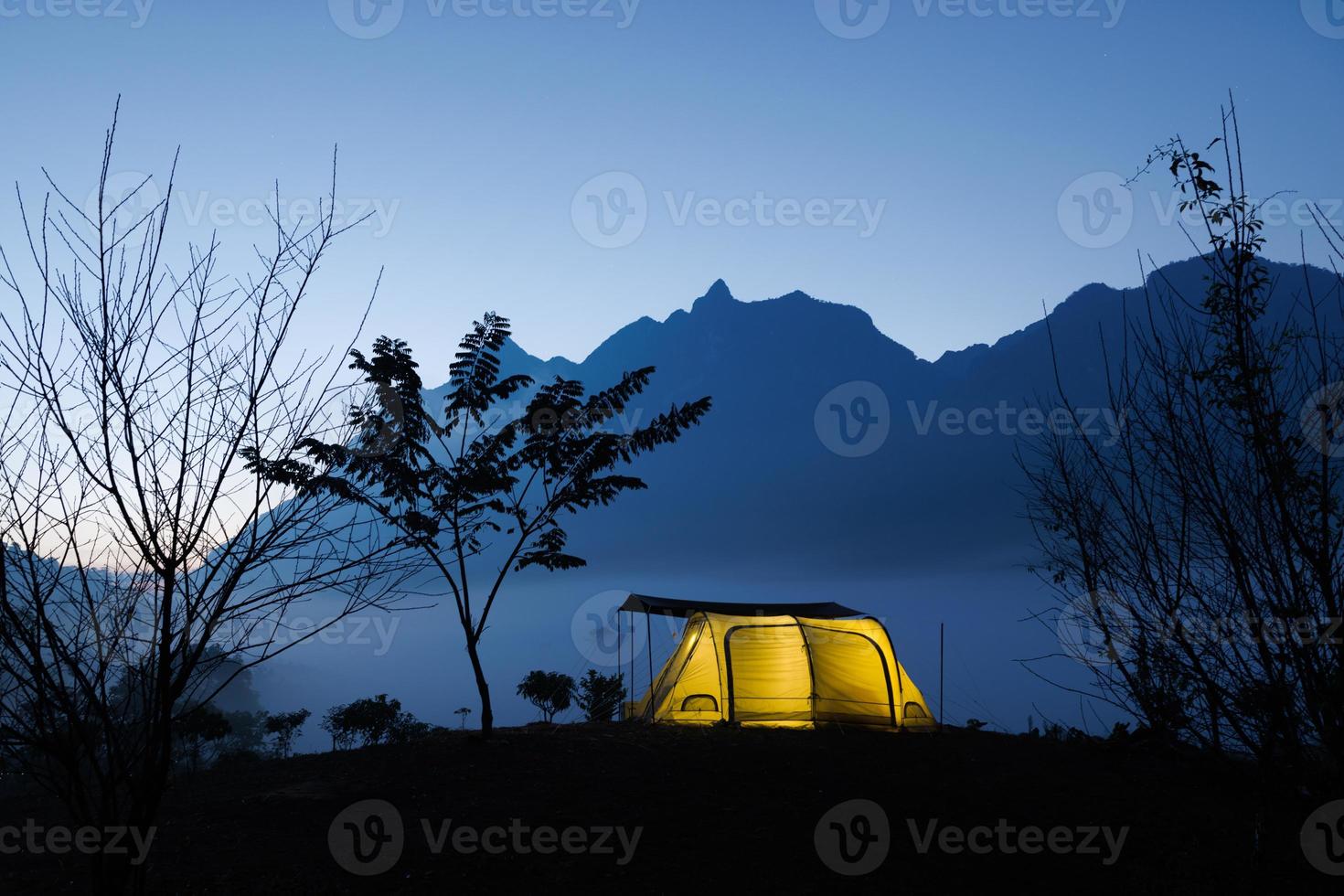 campamento y carpa en la noche frente a las montañas con nubes en el parque natural, concepto de turismo foto