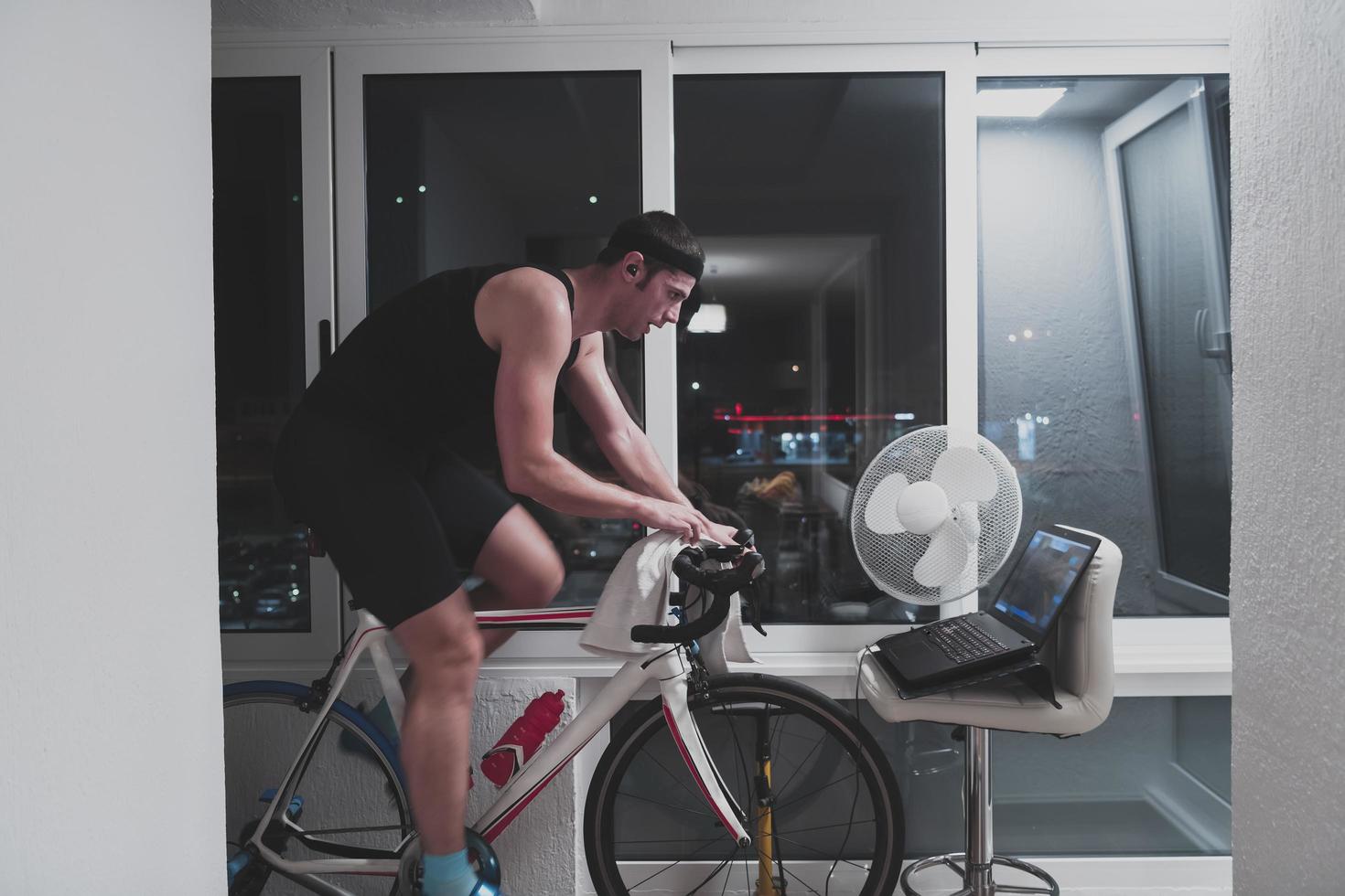 Man cycling on the machine trainer he is exercising in the home at night playing online bike racing game photo