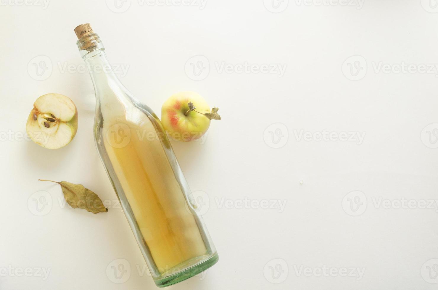 vista superior, una botella de vinagre de sidra de manzana con composición de manzana sobre fondo blanco foto