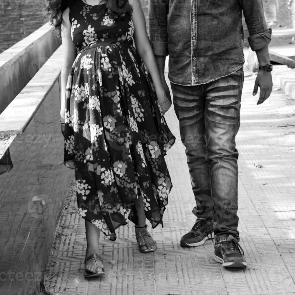 pareja india posando para una sesión de fotos de maternidad. la pareja está posando en un césped con hierba verde y la mujer está faluntando su panza en el jardín de lodhi en nueva delhi, india - blanco y negro