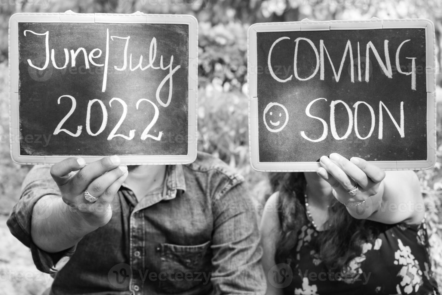 Indian couple posing for maternity baby shoot. The couple is posing in a lawn with green grass and the woman is falunting her baby bump in Lodhi Garden in New Delhi, India - Black and White photo