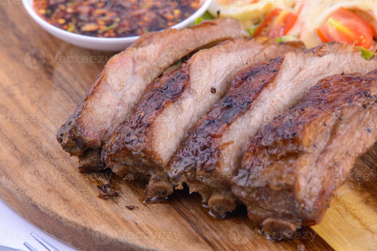 Roasted pork steak on the wooden plate with thai sauce. photo