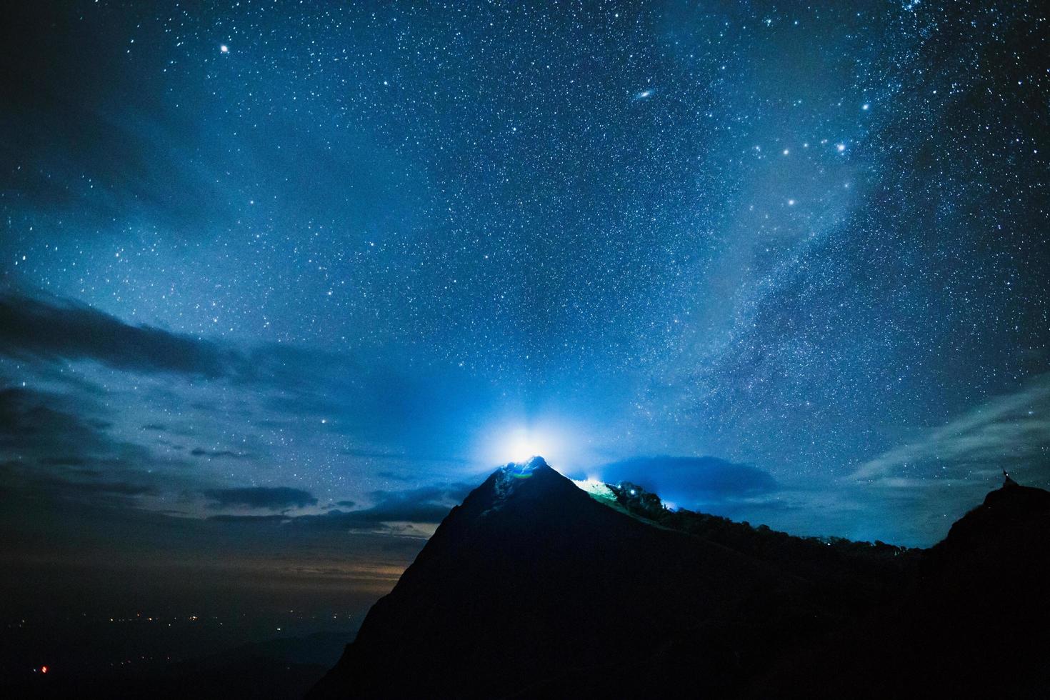 Young group of tourists enjoying in the camping at night, having a rest near campfire and colorful tent under beautiful night sky full of stars and milky way photo