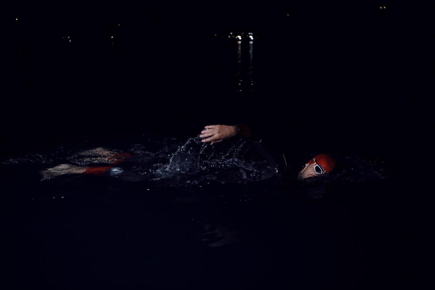 triathlon athlete swimming in dark night  wearing wetsuit photo