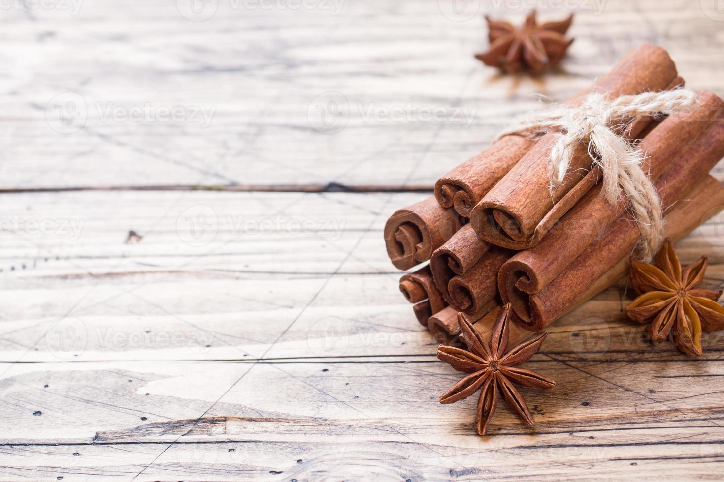 A few cinnamon sticks tied with thread and anise stars on a wooden background. Copy space. Selective focus. photo