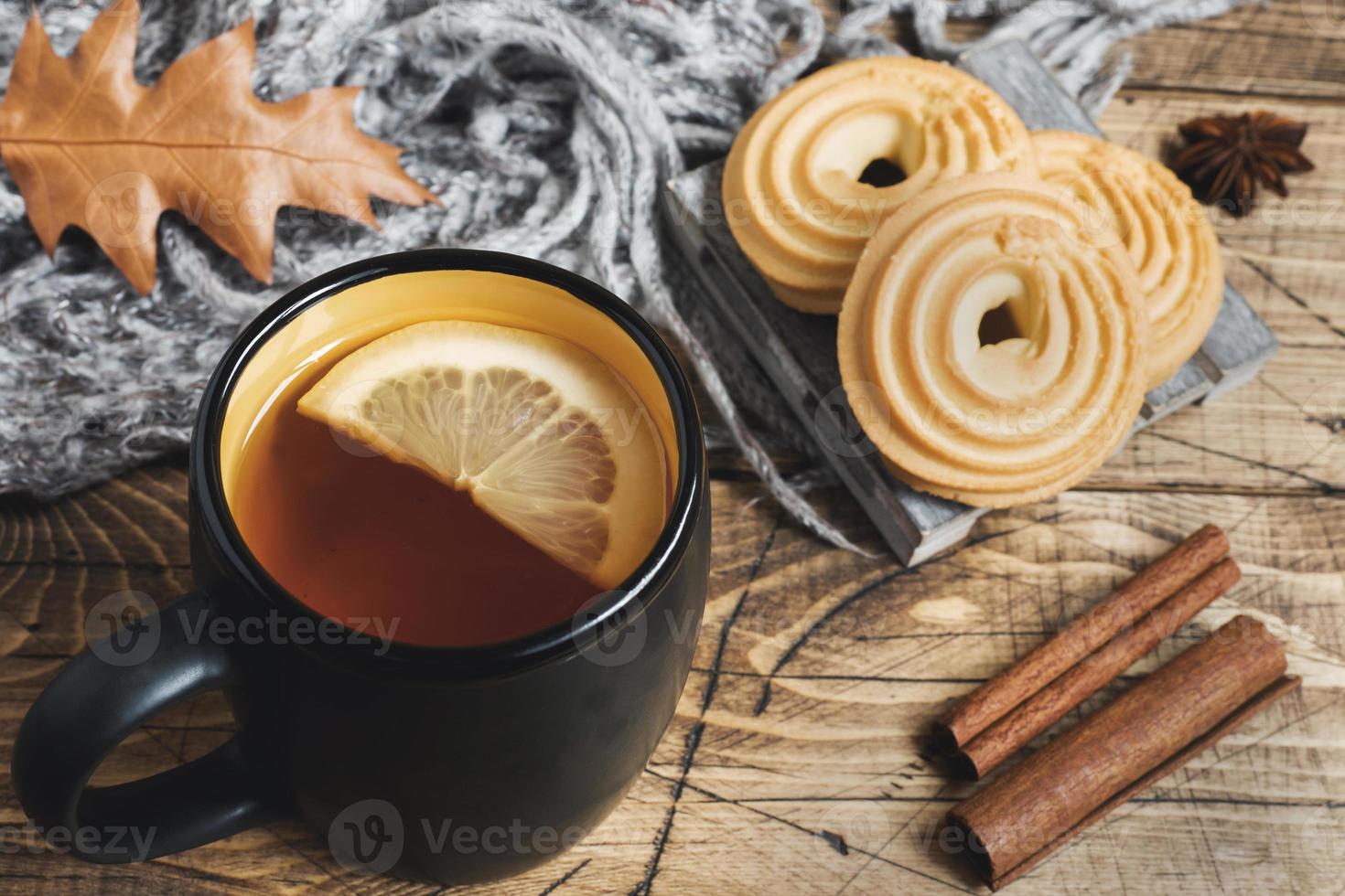 Autumn still life with cup of tea, cookies, sweater and leaves on wooden background. concept of cozy autumn, fall season photo