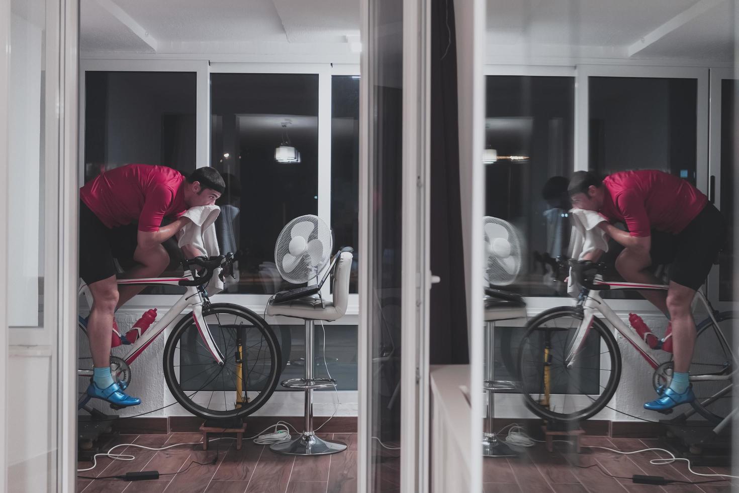 Man cycling on the machine trainer he is exercising in the home at night playing online bike racing game photo