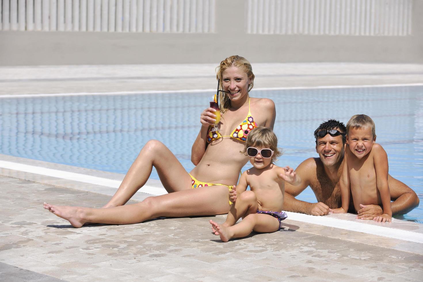 familia joven feliz divertirse en la piscina foto