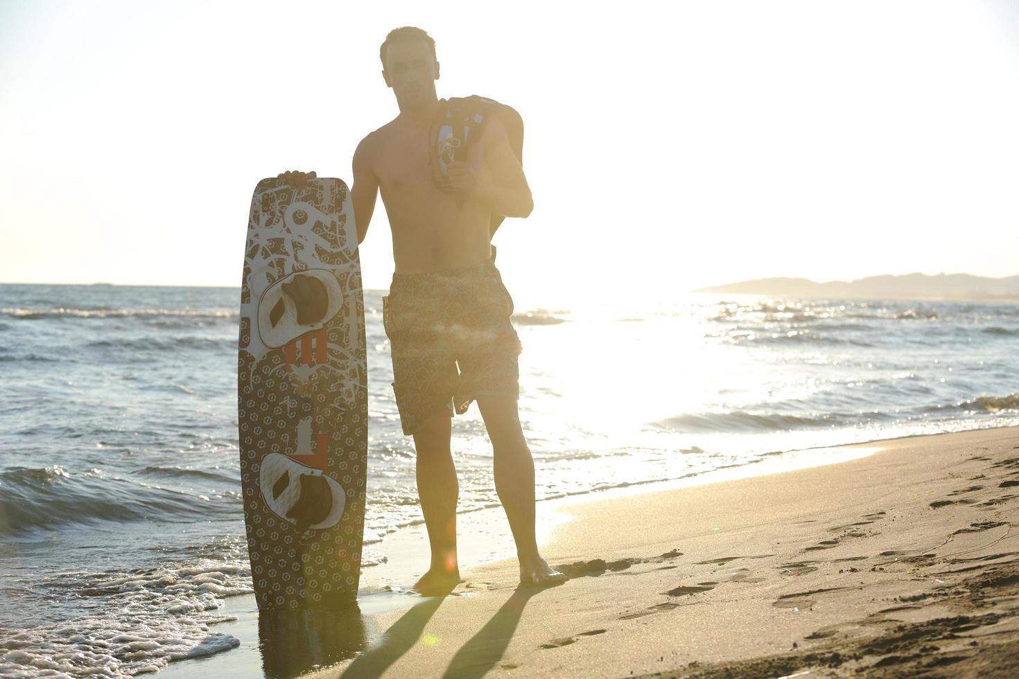 Portrait of a young  kitsurf  man at beach on sunset photo