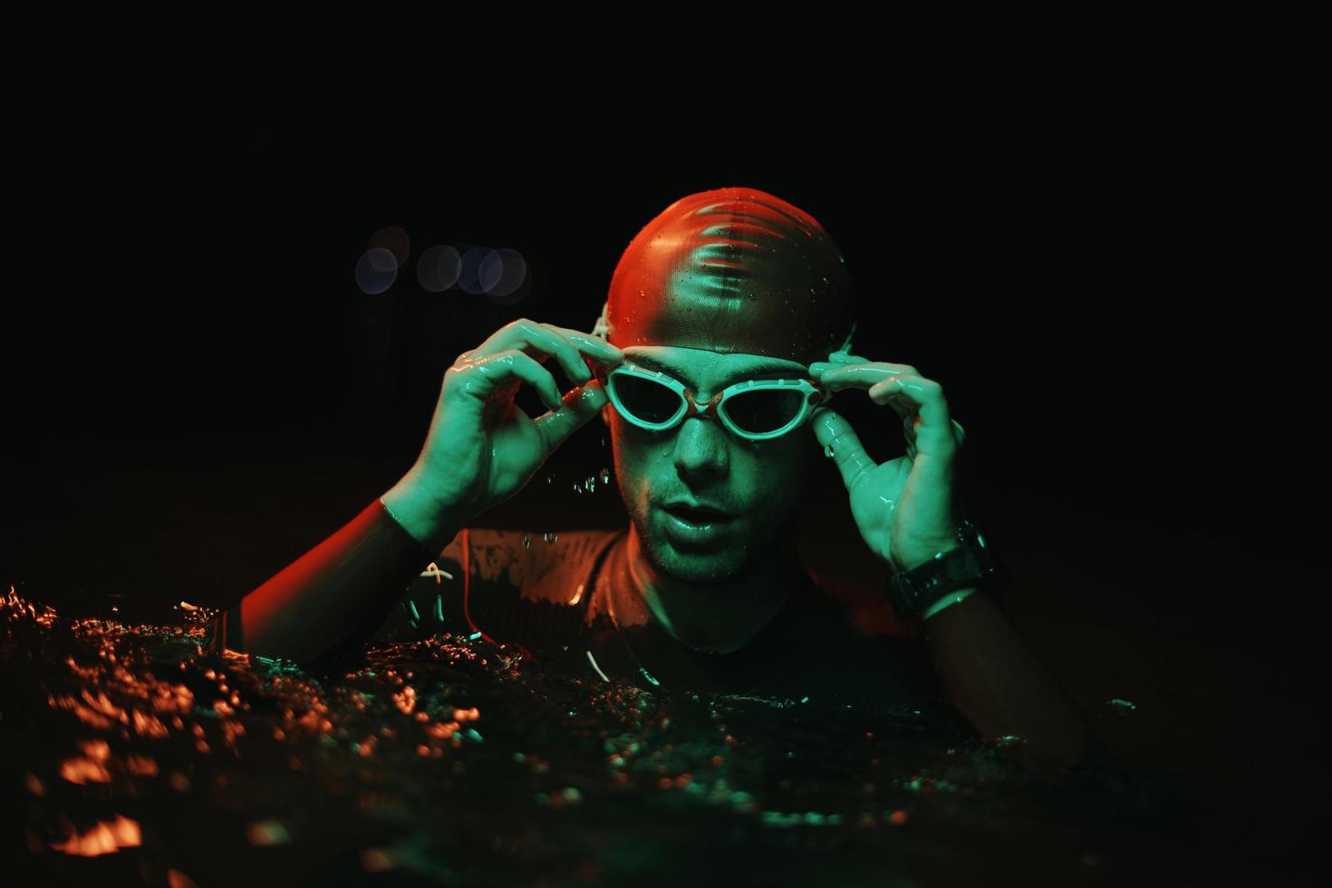 authentic triathlete swimmer having a break during hard training on night neon gel light photo