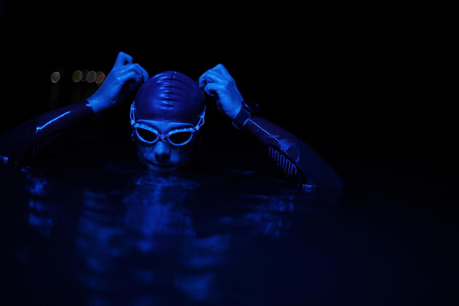 authentic triathlete swimmer having a break during hard training on night neon gel light photo