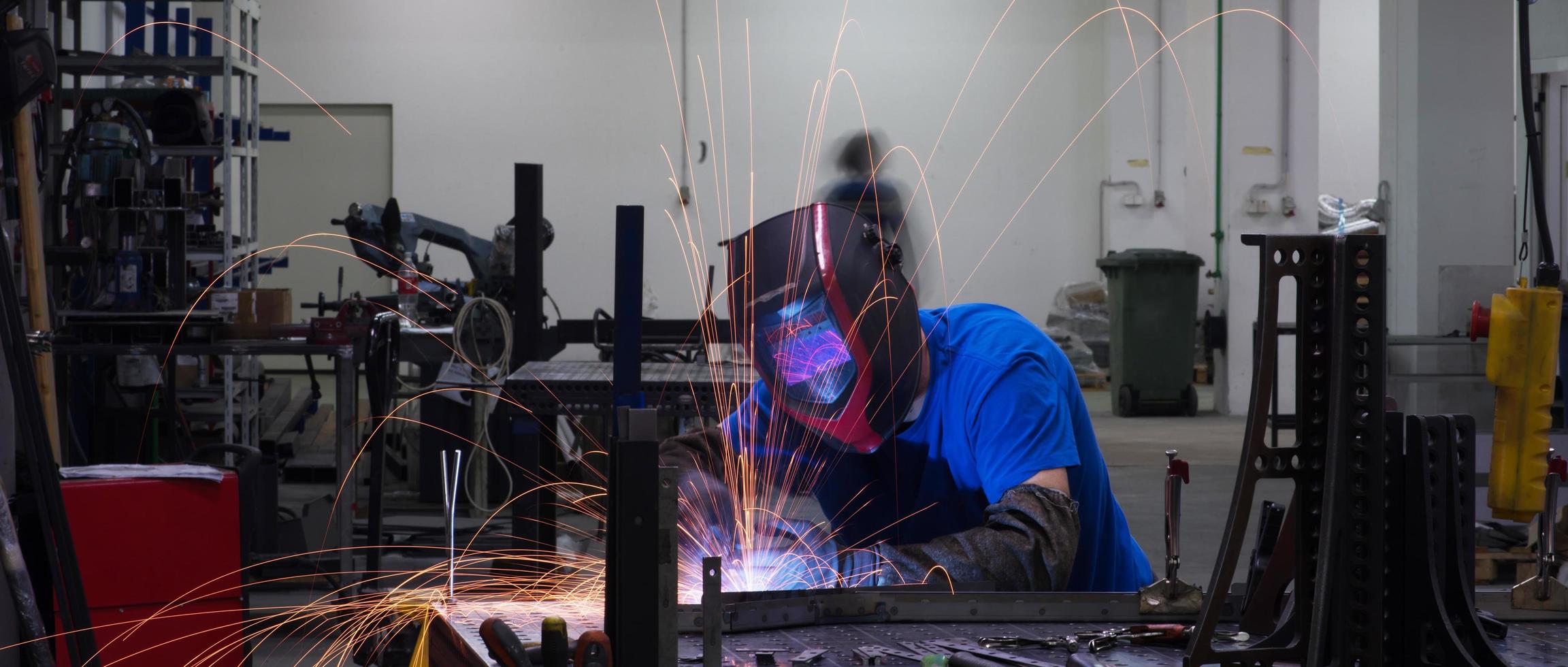 Professional Heavy Industry Welder Working Inside factory, Wears Helmet and Starts Welding. Selective Focus photo