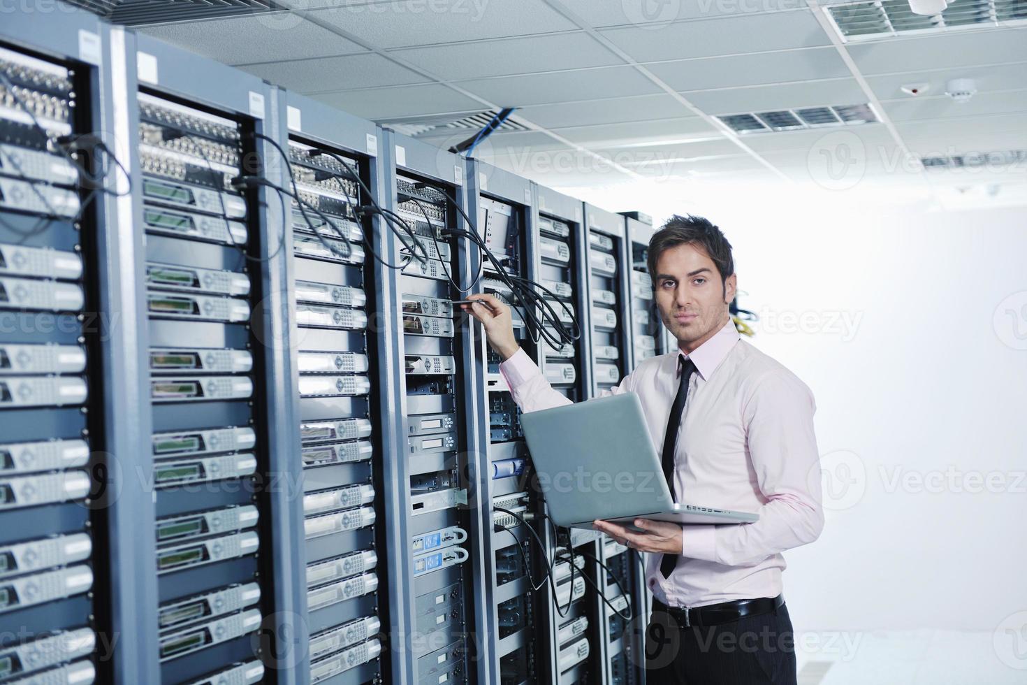 businessman with laptop in network server room photo