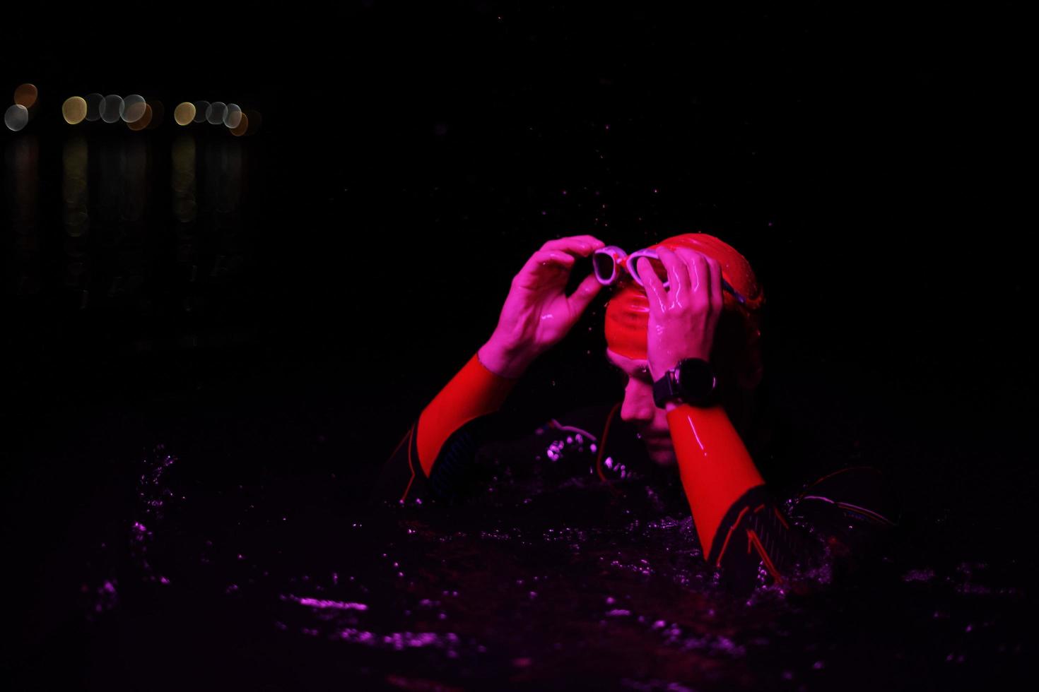 authentic triathlete swimmer having a break during hard training on night neon gel light photo