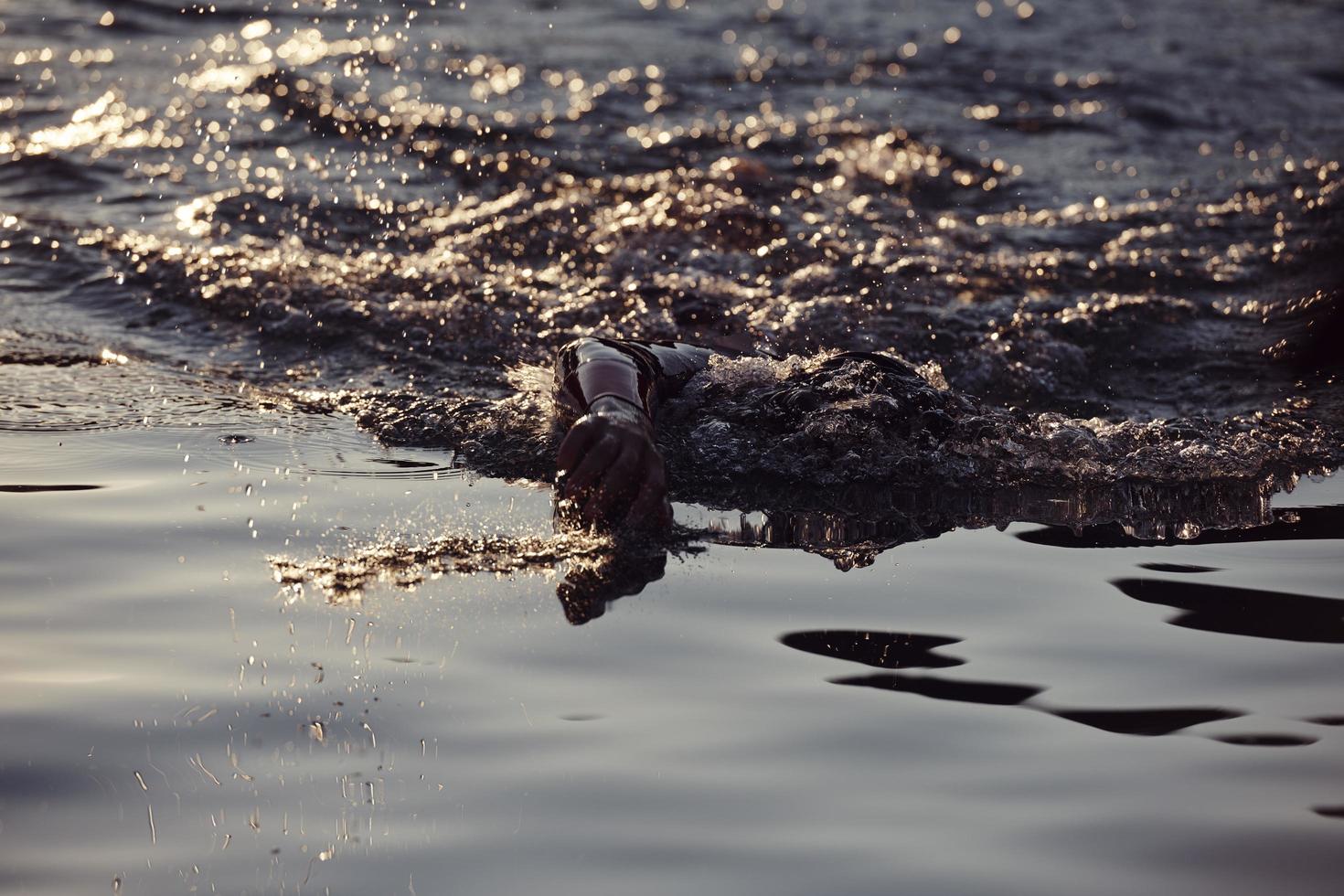 atleta de triatlón nadando en el lago al amanecer usando traje de neopreno foto