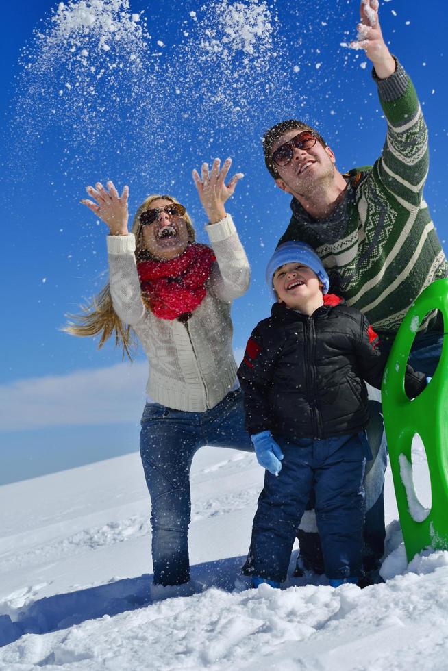 family having fun on fresh snow at winter vacation photo