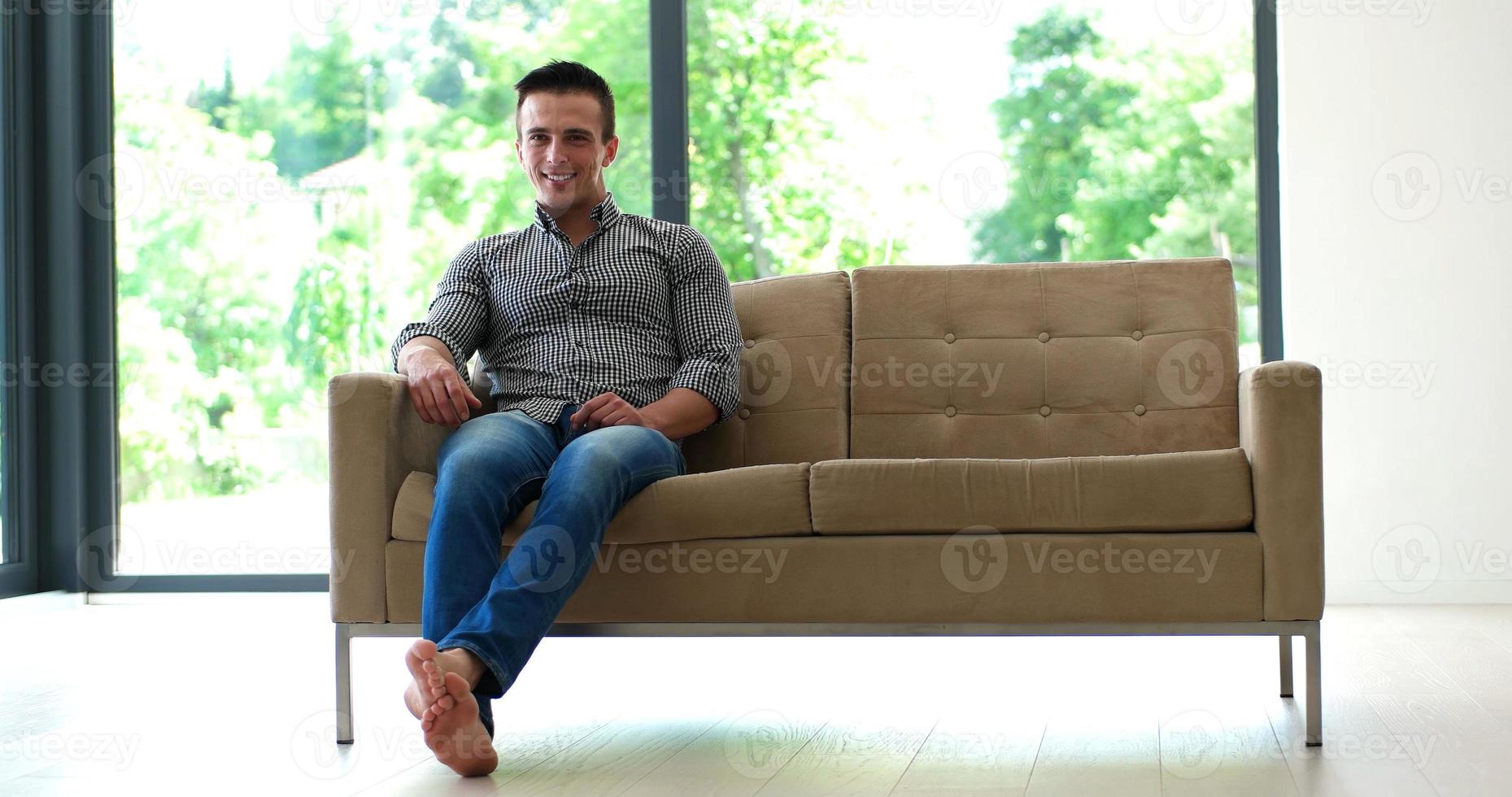 Man is Laying on Couch at Home and Using Tablet photo