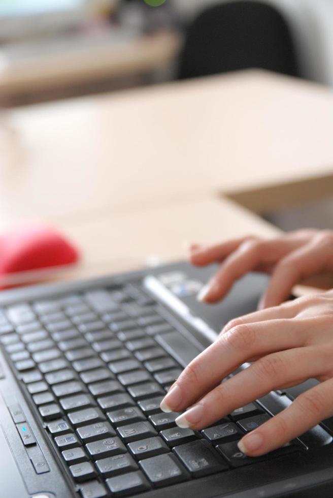 manos de mujer escribiendo en el teclado de la computadora portátil foto