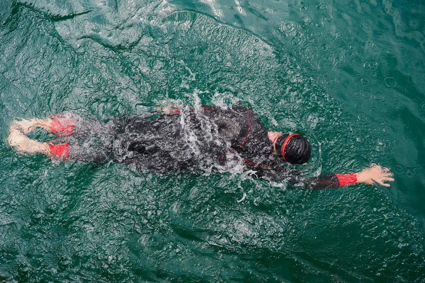 triathlon athlete swimming on lake wearing wetsuit photo