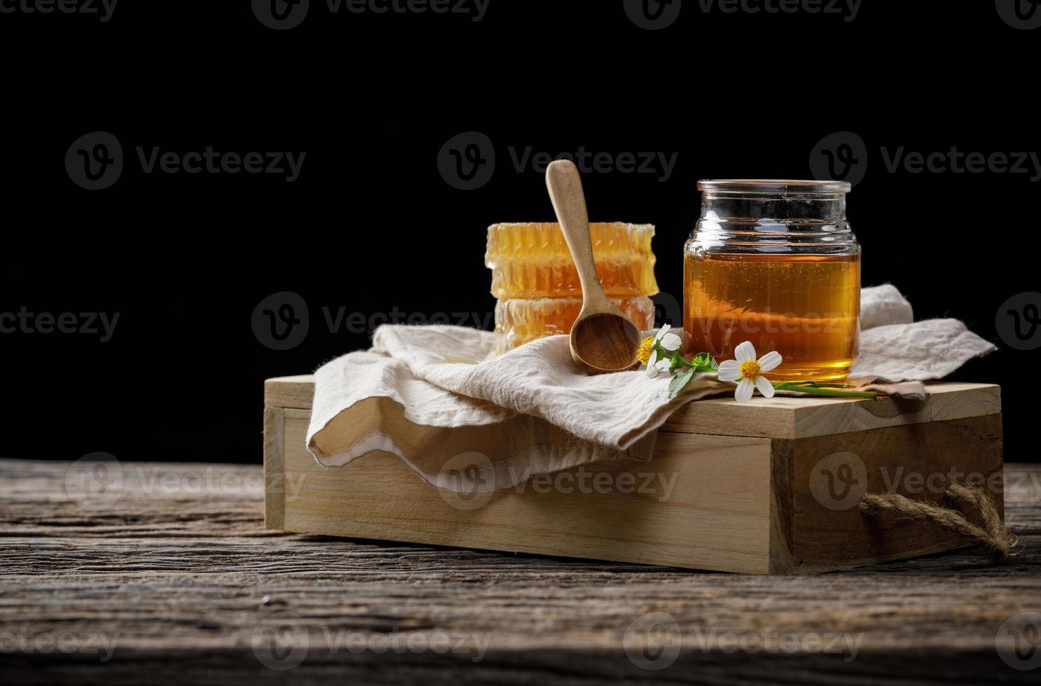 Honey bee in jar and honeycomb with honey dipper and flower on wooden table, bee products by organic natural ingredients concept, copy space for your text photo