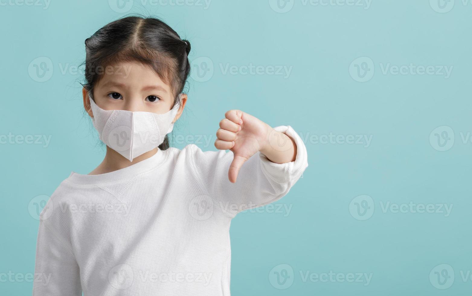 Asian little child girl wearing respirator mask for stop coronavirus outbreak, New virus Covid-19 from Wuhan China concept, Empty space isolated on blue long banner photo