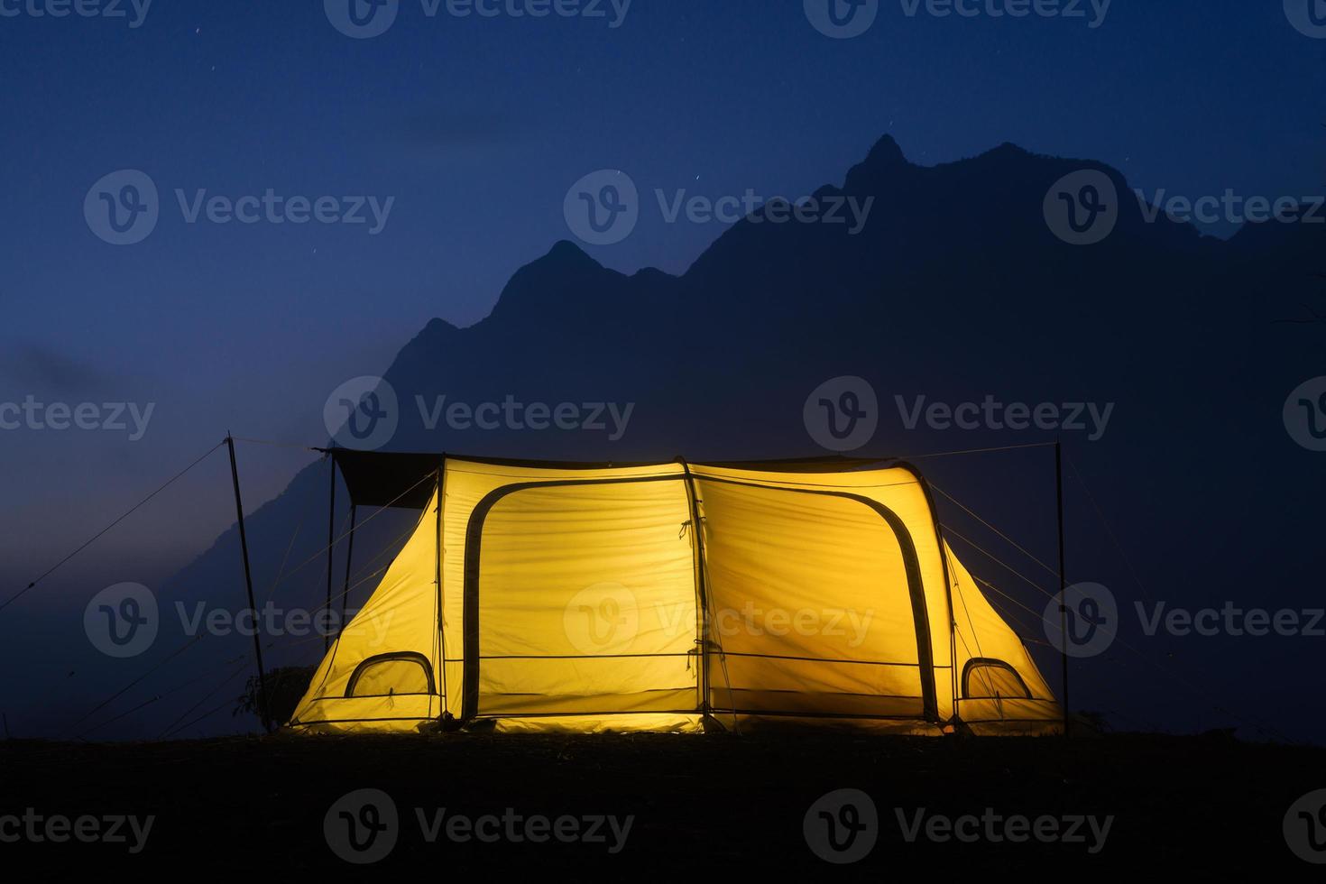 Glowing yellow tent in the mountains with cloud in natural park, Tourism concept photo
