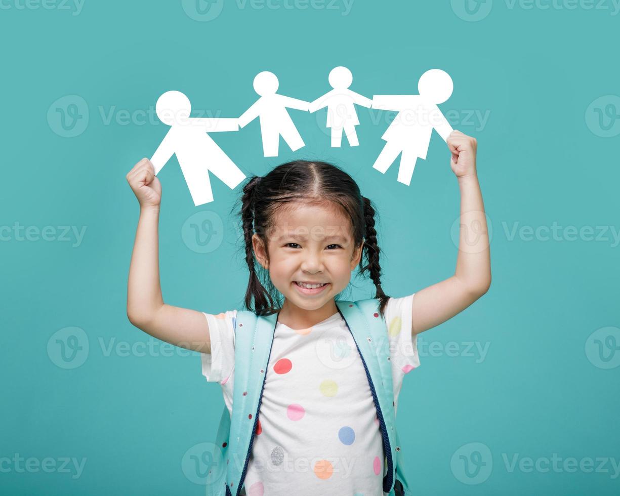 niña asiática feliz sonriente sosteniendo un corte de papel de la familia, espacio vacío en una foto de estudio aislada en un fondo azul colorido, concepto de familia feliz