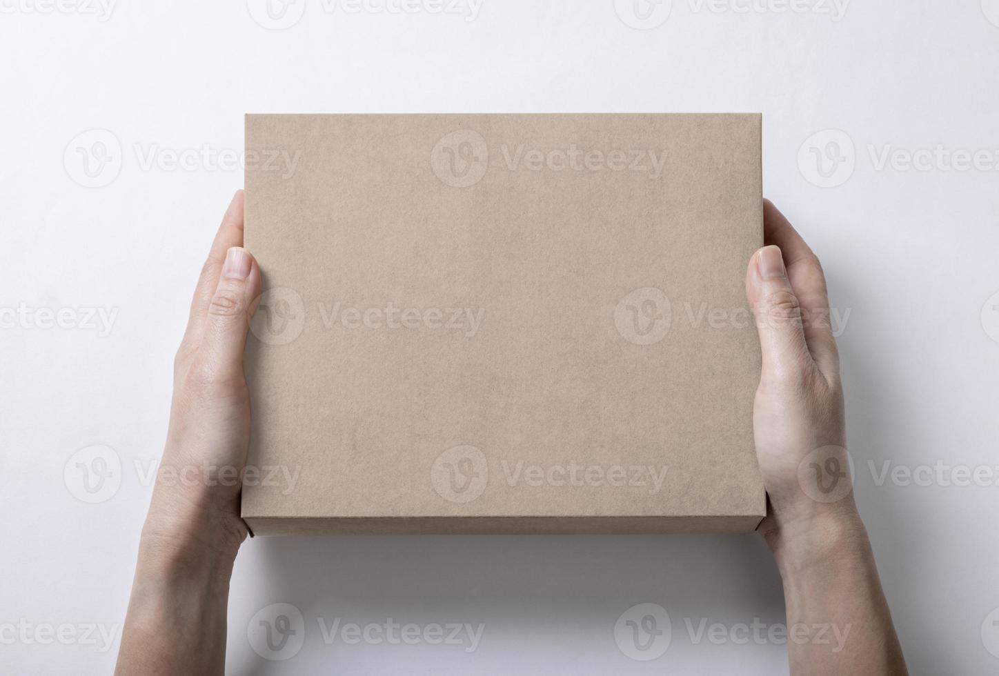 Hand holding cardboard box packaging mockup template with copy space for your logo or graphic design, isolate on white background photo