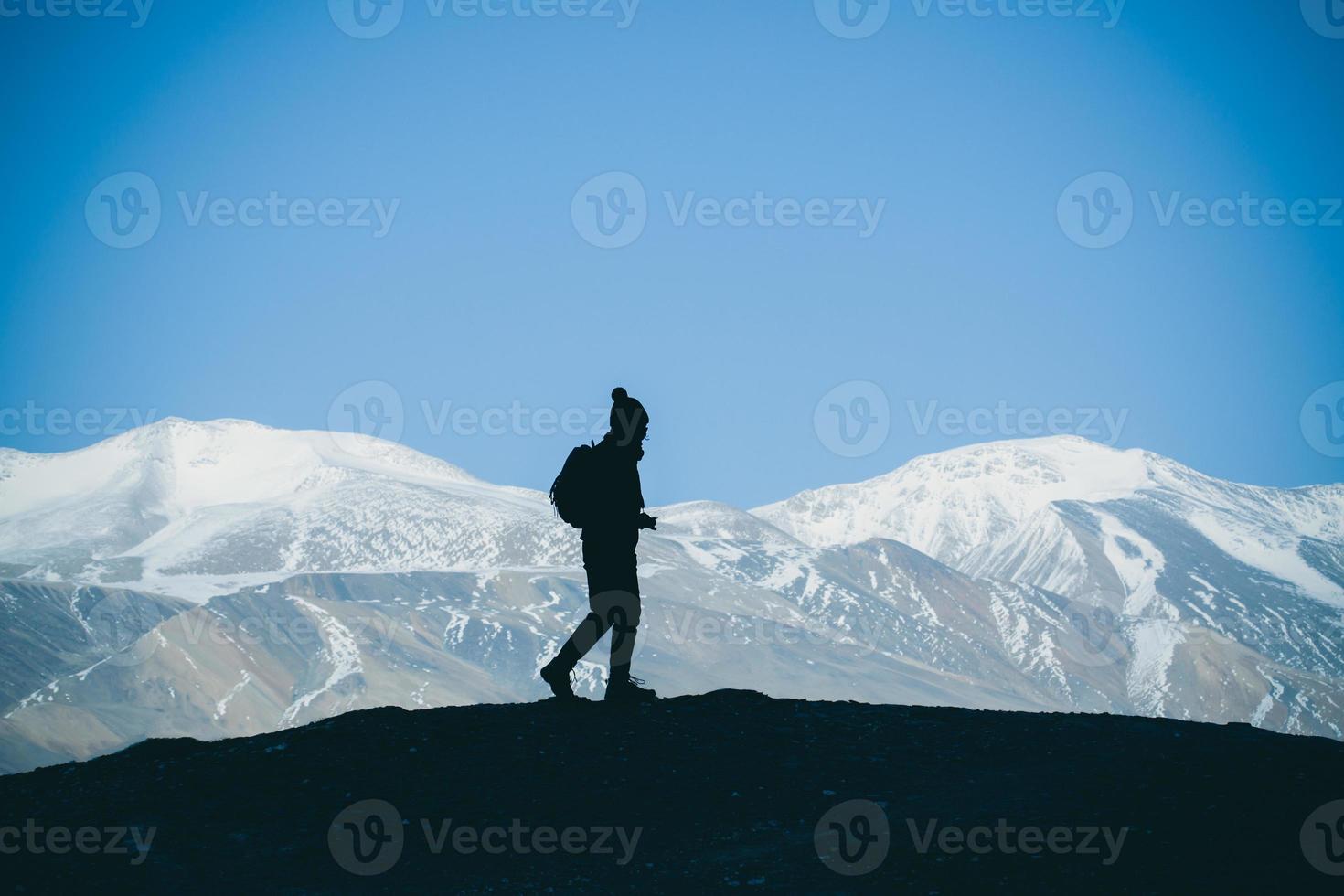 silueta de mujer excursionista se encuentra en la roca en la hermosa vista de las montañas del nevado lago tso moriri en leh ladakh india, concepto de éxito foto