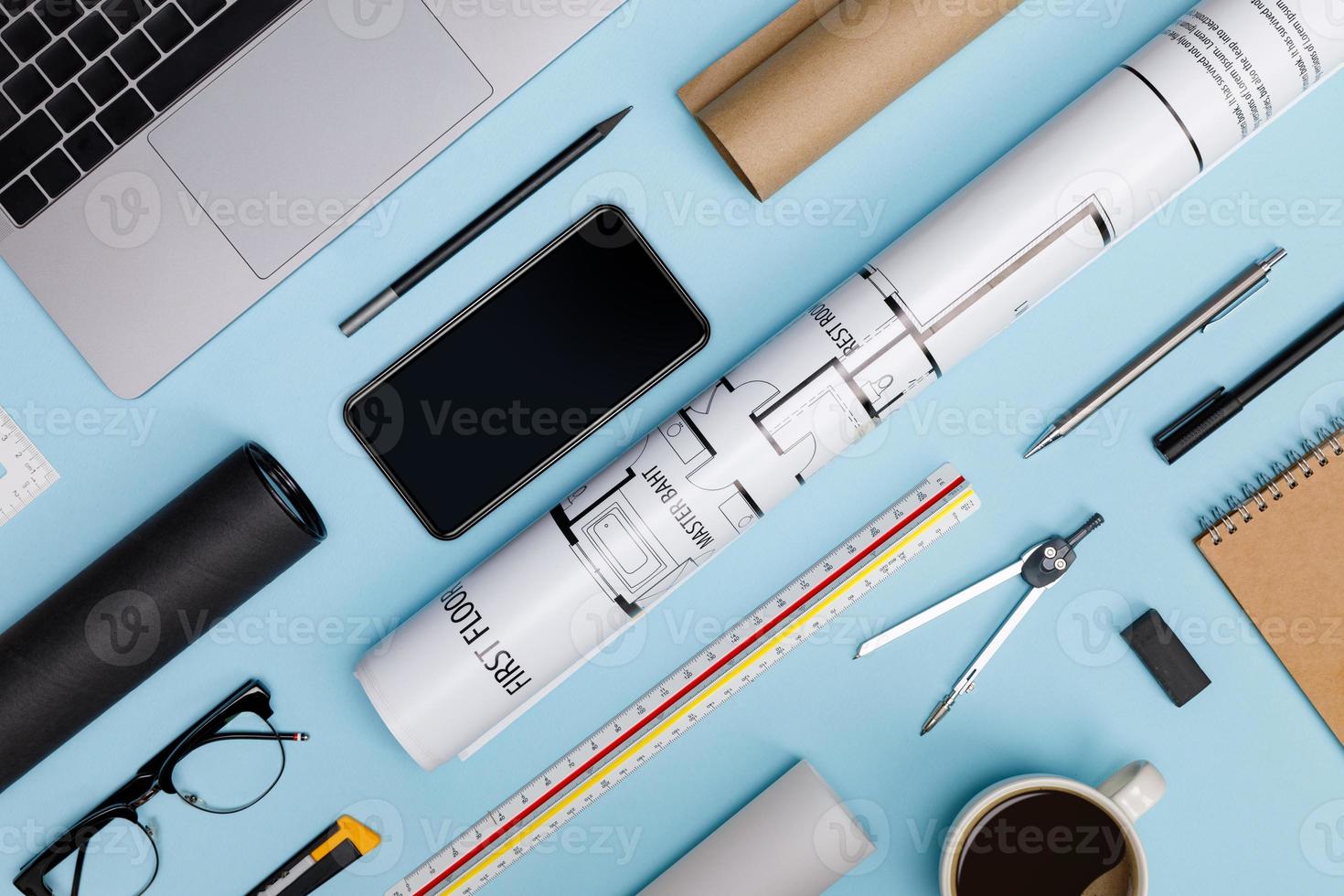 Creative flat lay of architects blue table with laptop computer, roll blueprints, architectural project plan, engineering tools, office supplies, isolated on blue background, Workspace for designer photo