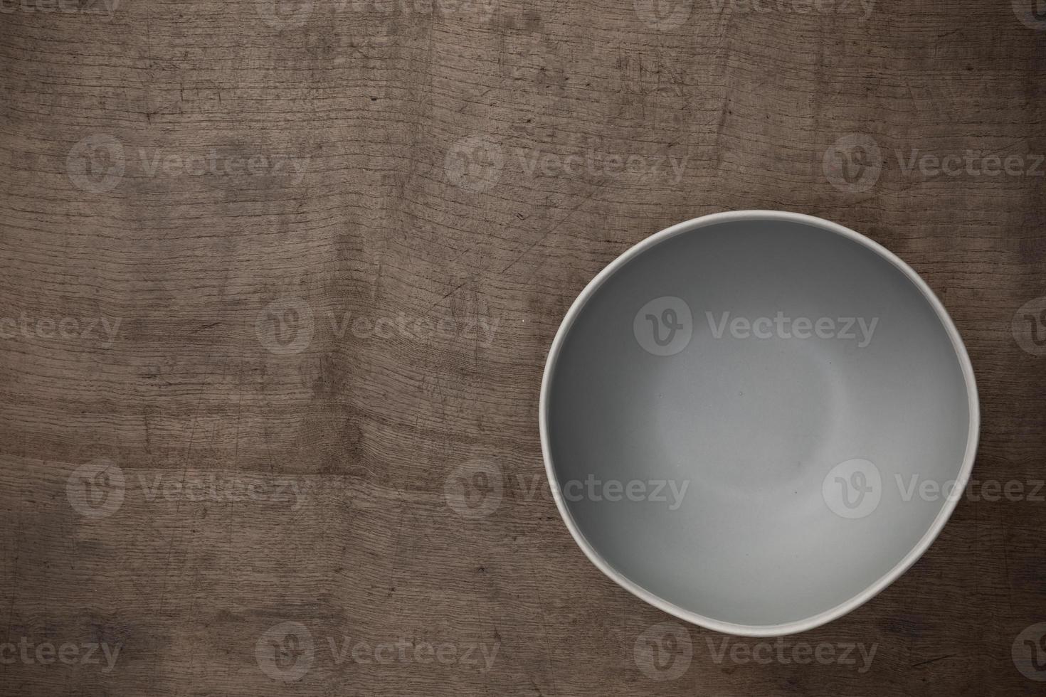 Empty blank gray ceramic round bowl on wooden table blackground with copy space, Top view of traditional handcrafted kitchenware concept photo