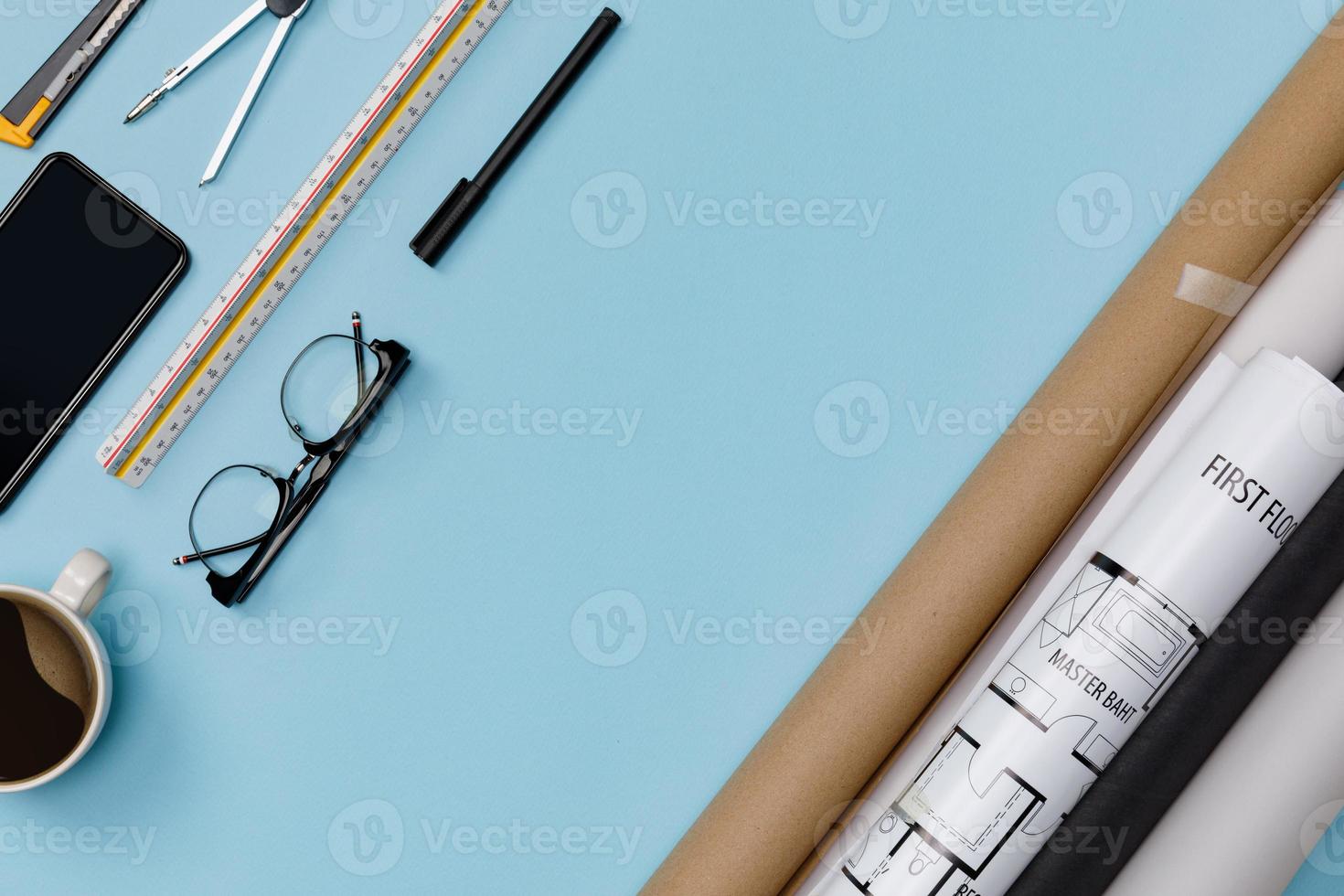 Creative flat lay of architects blue table with roll blueprints, architectural project plan, engineering tools, office supplies, isolated on blue background, Workspace for designer concept photo