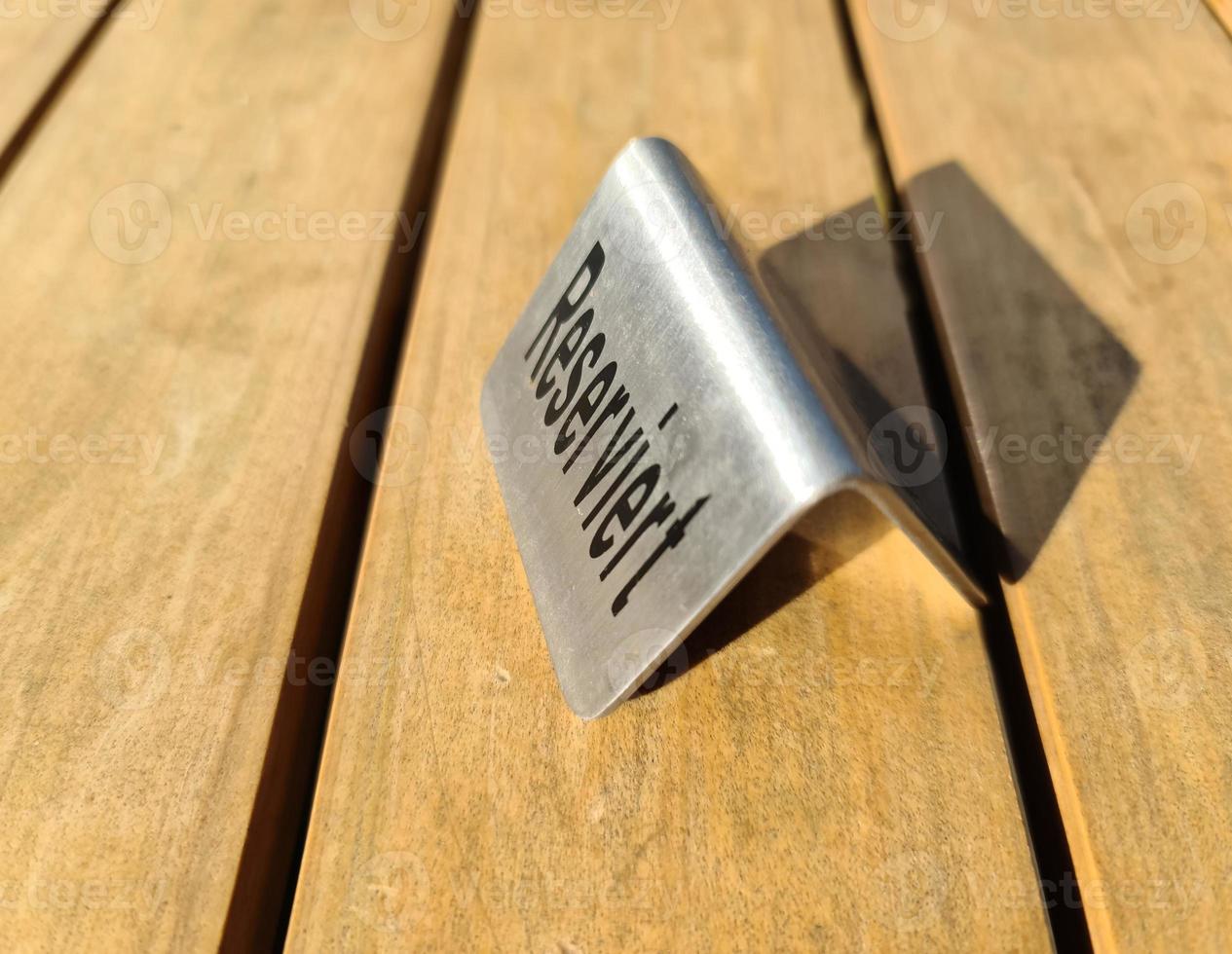 Metallic sign on a wooden table with the german word for reserved on it. photo