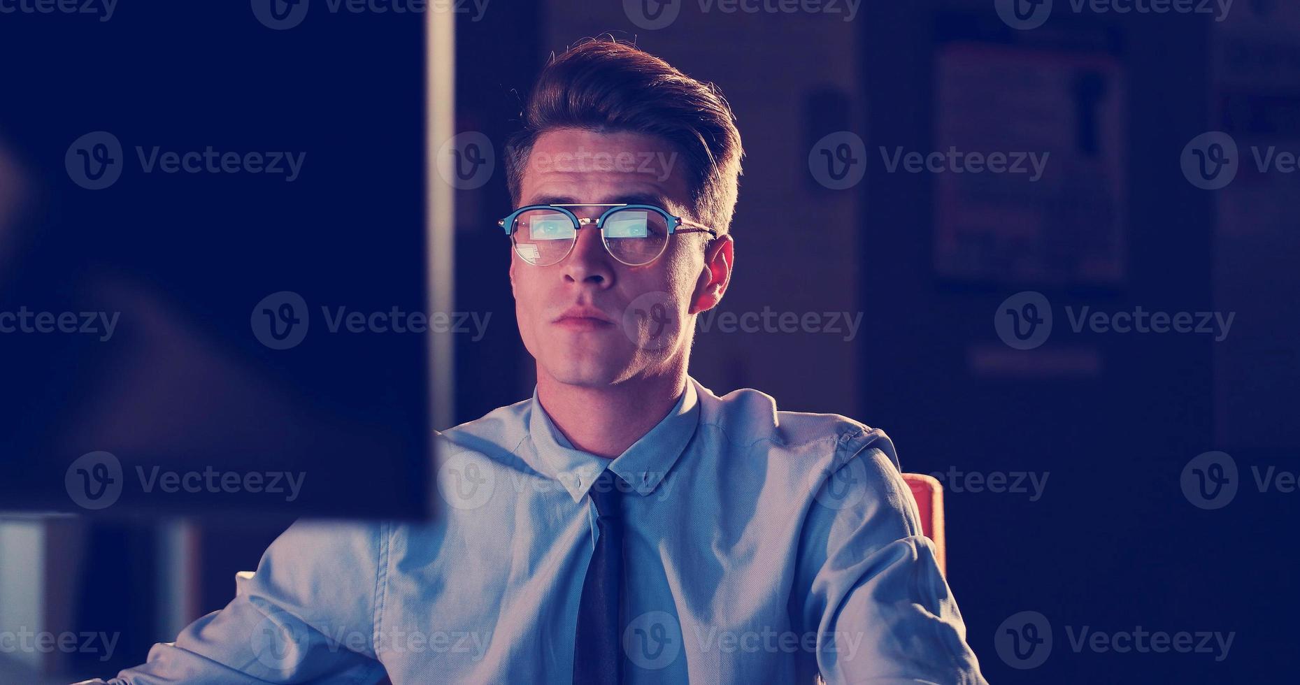 man working on computer in dark office photo