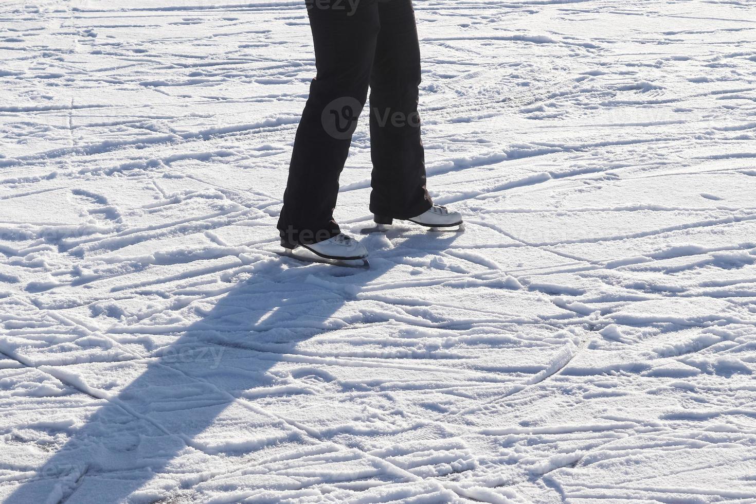 Close up on womans feet wearing ice skating boots and standing on ice. photo