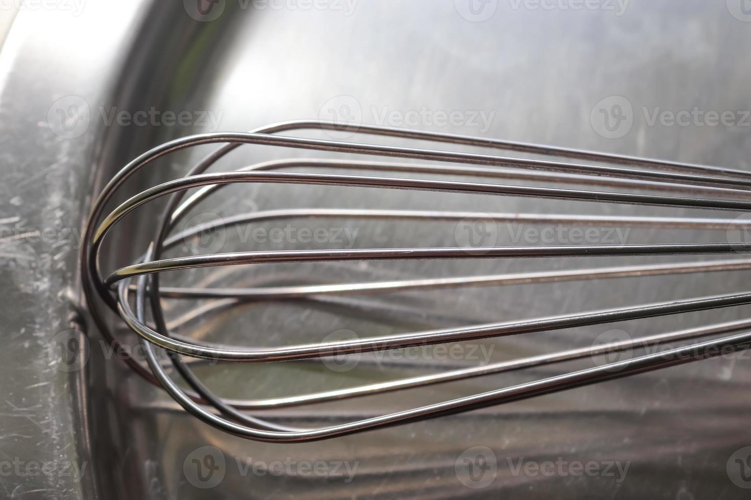 Manual hand mixer for blending, beating, Egg beater isolated on metal background. Metal stainless steel kitcenware utensil. photo