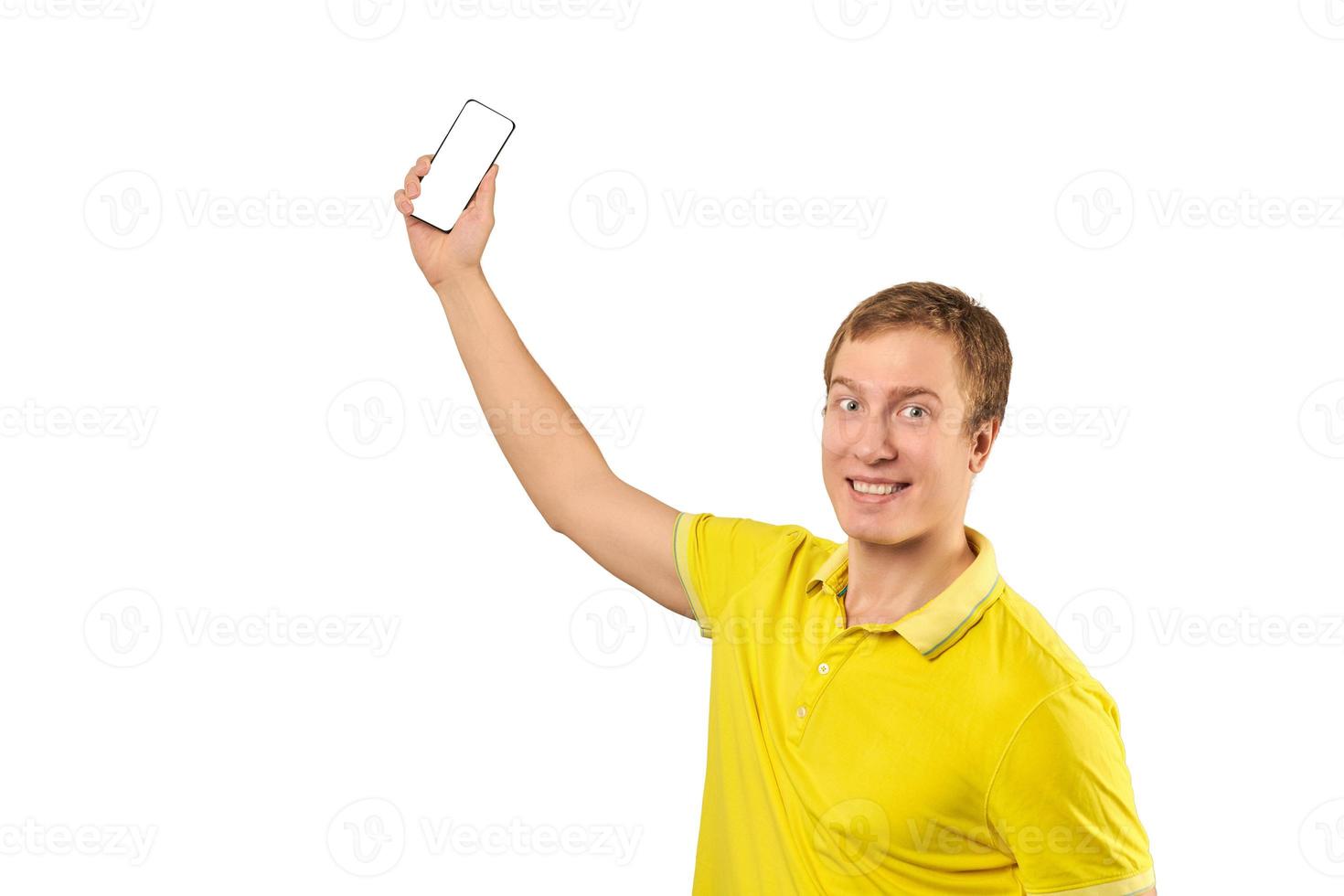 Funny guy in bright yellow T-shirt video chatting using video call with phone, smiling young man photo