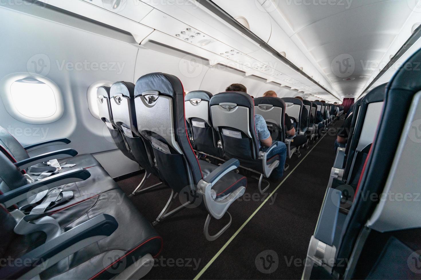 Airplane cabin seats with passengers. Economy class of new cheapest low-cost airlines. Travel trip to another country. Turbulence in flight. photo