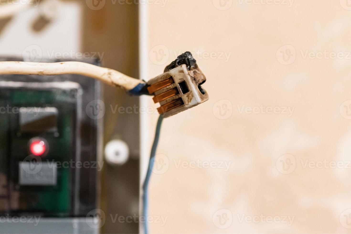 Burned wire, splicing connector, electrical terminal block of nonflammable, fireproof material. Faulty wiring or negligent electrical work. Dangerous short circuit accident. photo