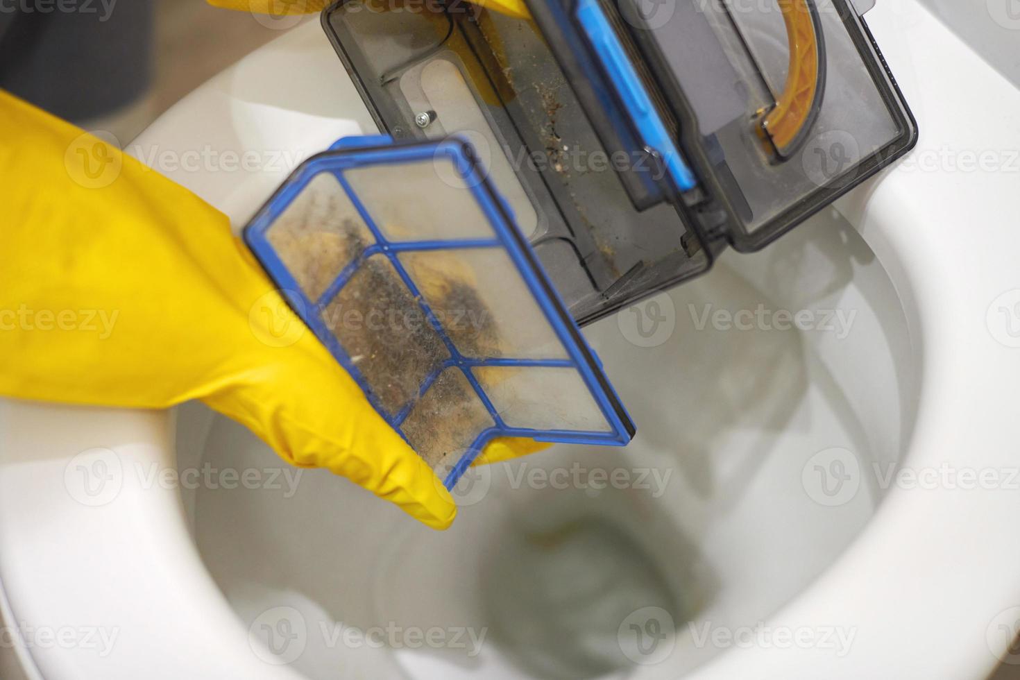 Hands in rubber gloves throw out trash in toilet, close up. photo