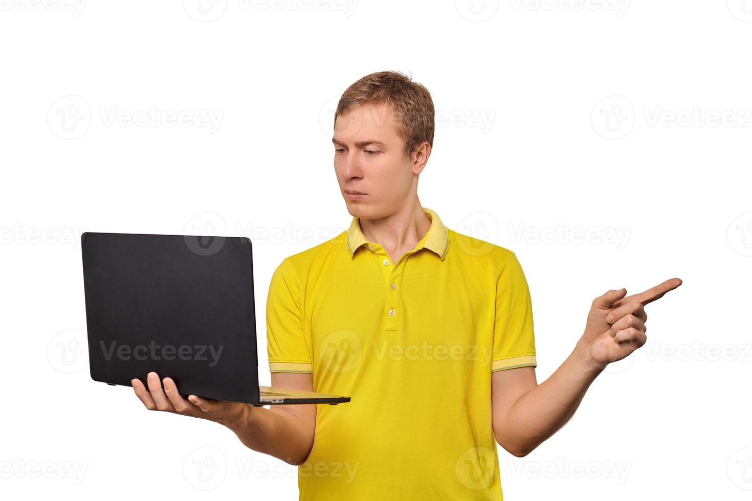 Puzzled young man with laptop pointing with finger isolated on white background, male confused face photo