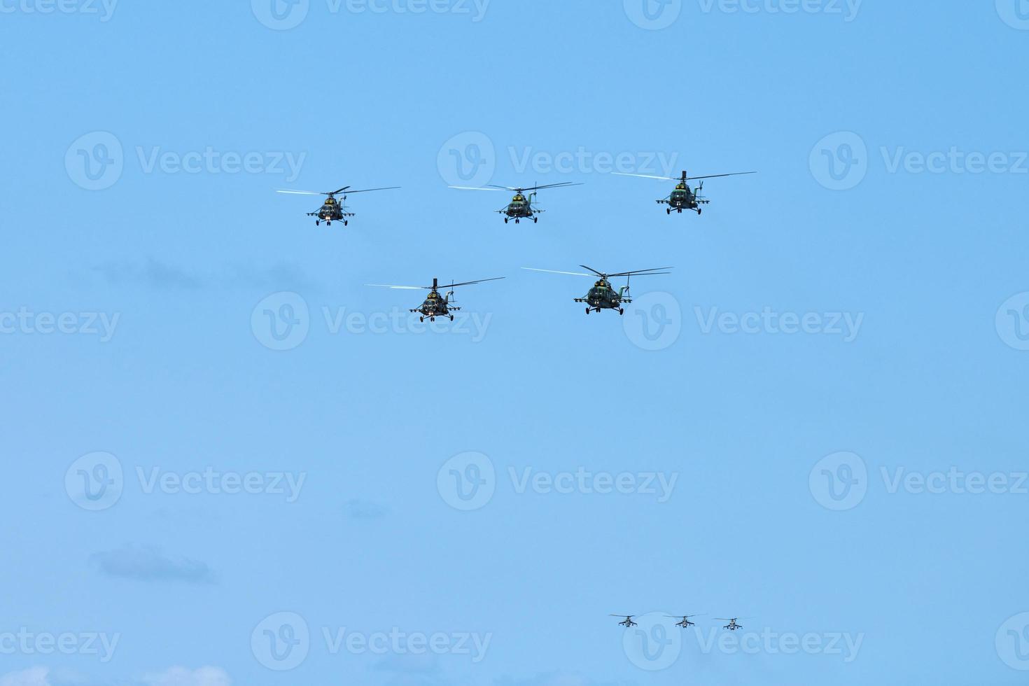 Military helicopters flying in blue sky performing demonstration flight, aerobatic team, air show photo