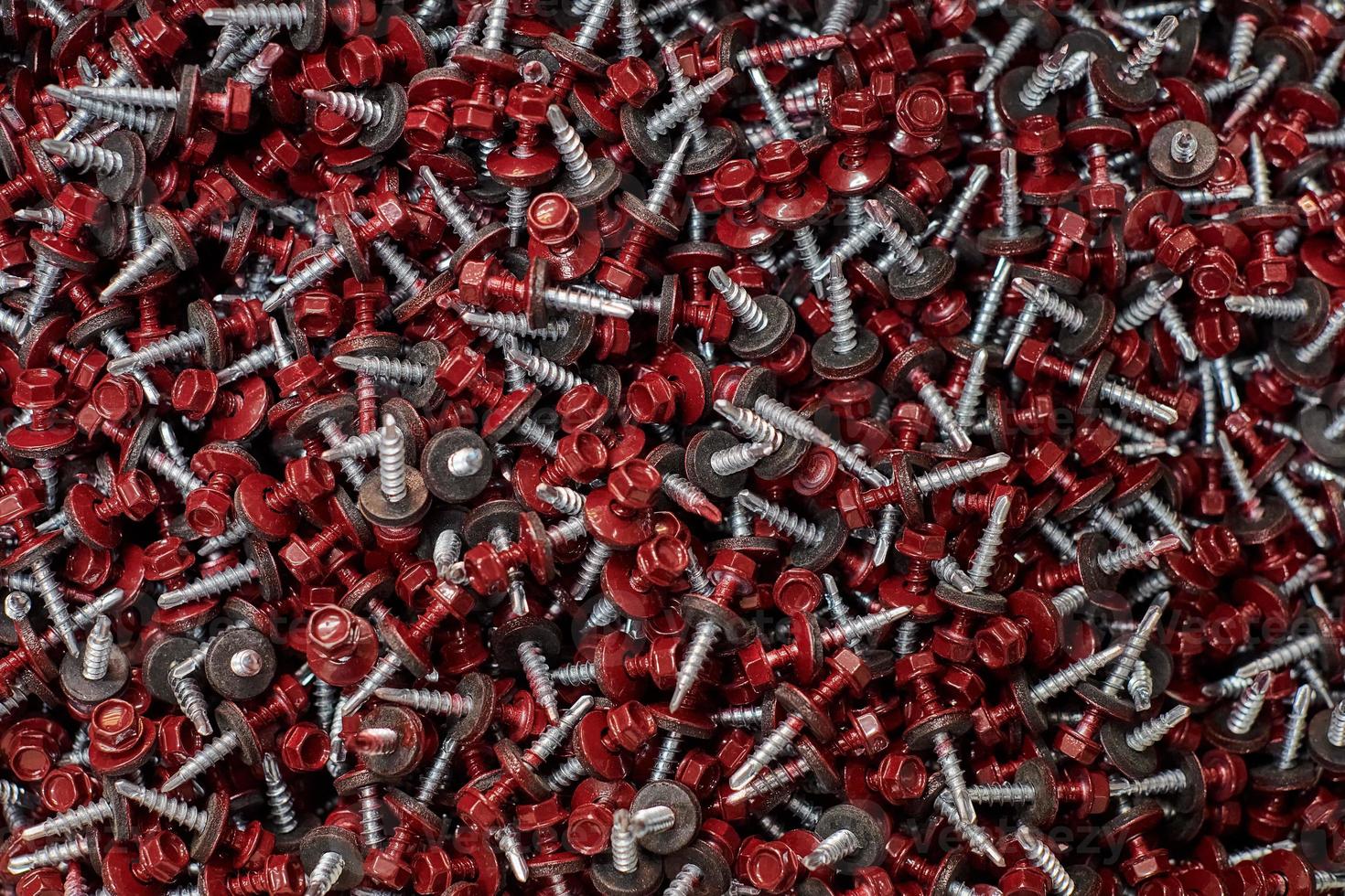 Bunch of galvanized self-drilling screws with washer and red hexagonal head, hardware background photo