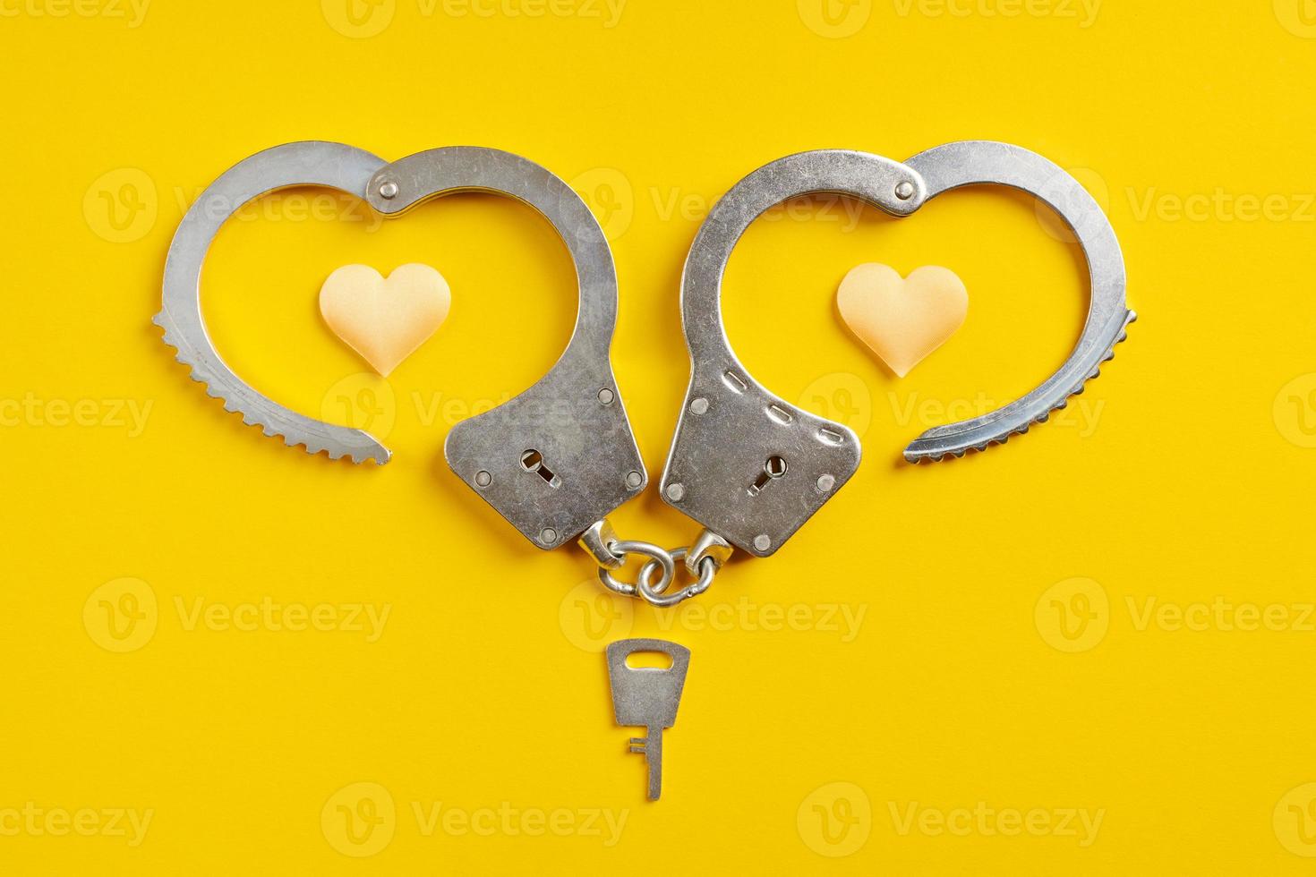 Handcuffs smile shape on yellow background. Freedom concept. photo